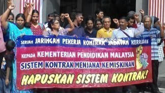 Contract workers holding a banner that says "Hapuskan sistem kontrak!"